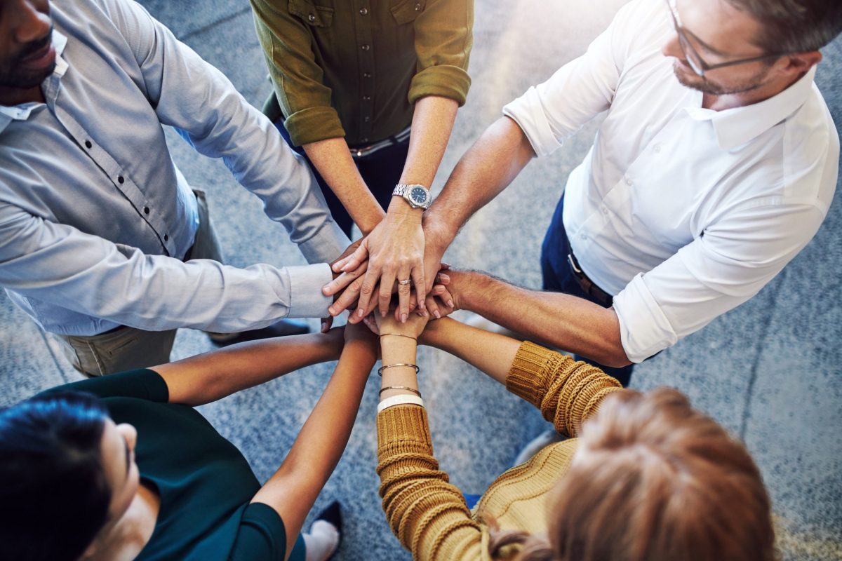 Teamwork, hands in a huddle and working together with a team or group of business people and colleagues standing in the office. Togetherness, unity and motivation between creative coworkers at work